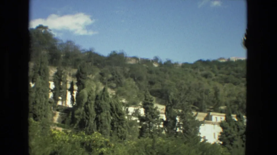 Granada hillside footage from 1978 with dense trees, white structures, and a partly cloudy sky within an 8mm frame.