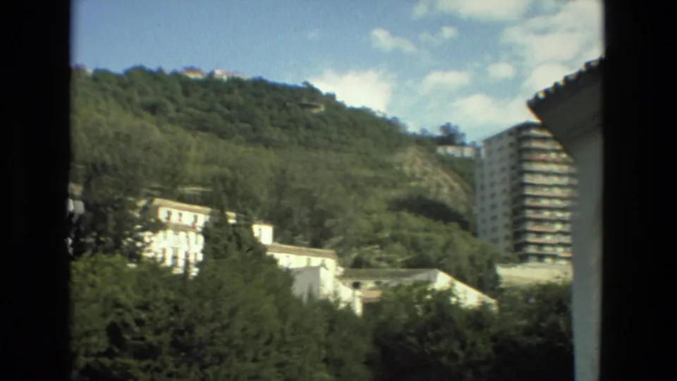 Granada, Spain, in 1978, with white hillside buildings, dense greenery, and a tall apartment block at the right edge.