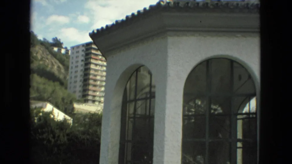 1978 Granada visitor footage shows a white arched gazebo-like building in the foreground with hillside housing and greenery behind it.