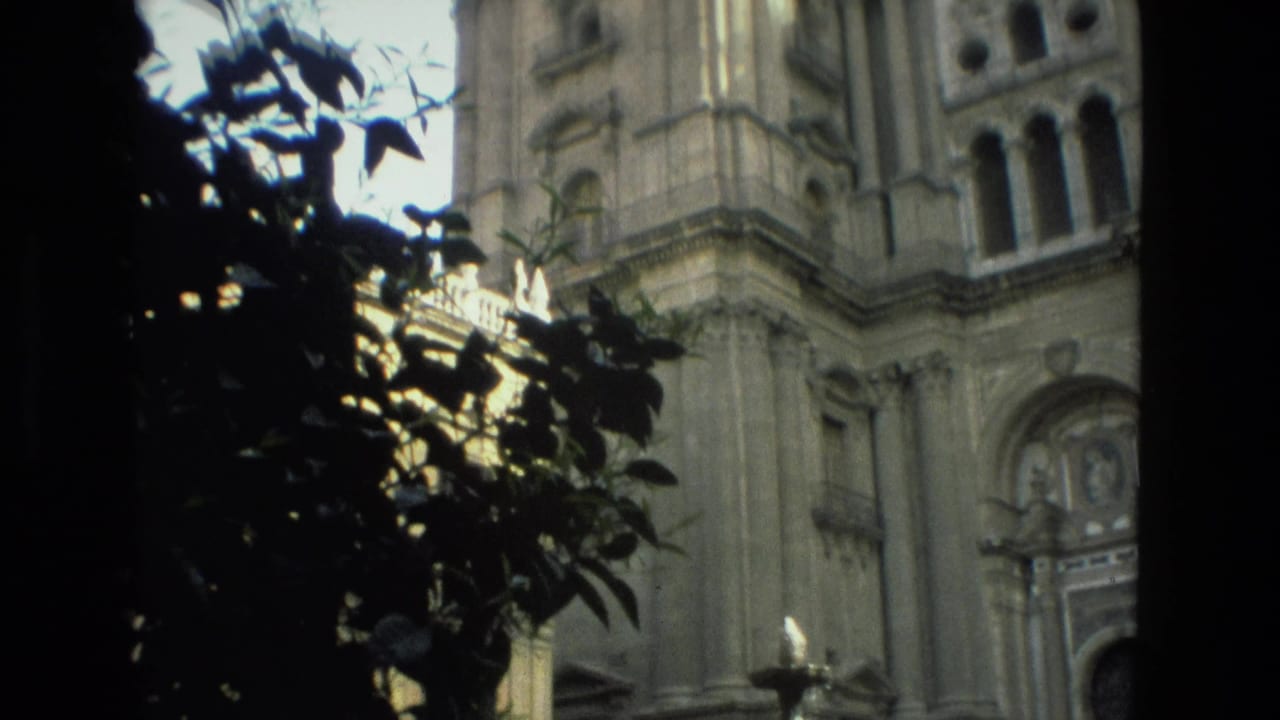 1978 Granada travel frame showing a stone cathedral facade, arched entrance, and foreground foliage in shadow.