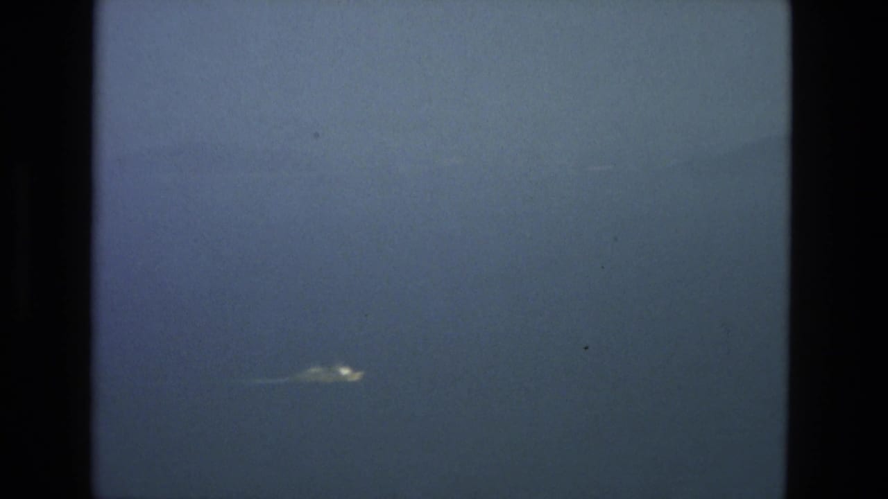 A distant bright elongated object appears in the blue-gray sky in 1978 8mm footage identified as Granada, Spain, with dark film borders and visible grain.