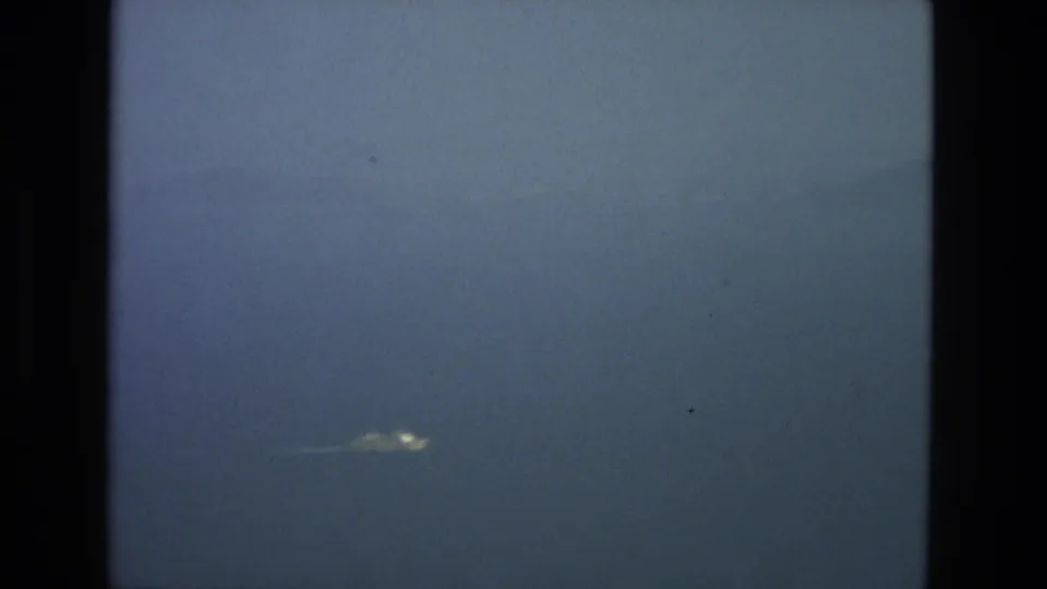 A distant bright elongated object appears in the blue-gray sky in 1978 8mm footage identified as Granada, Spain, with dark film borders and visible grain.