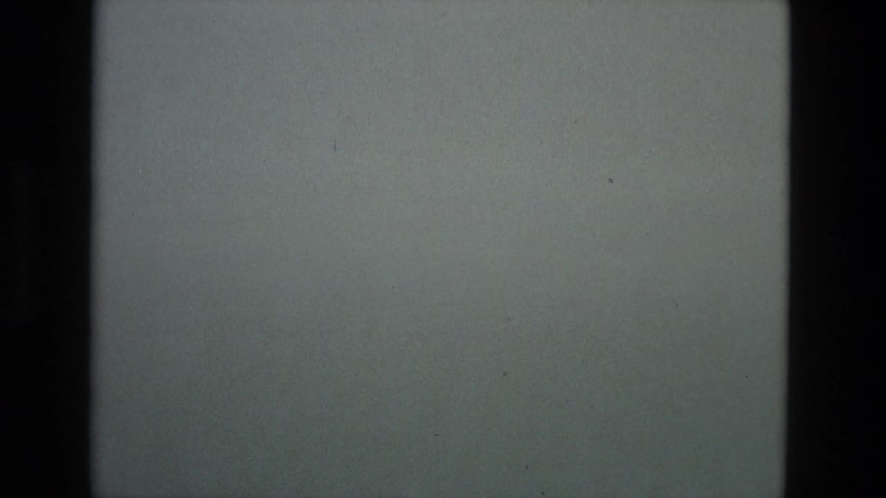 Dim grey sky over a dark distant ridge, with visible film borders and grain.