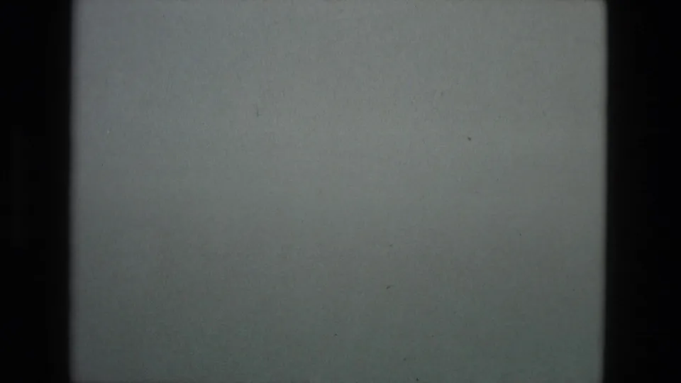 1978 Granada home-movie frame showing a muted grey sky above a barely visible dark mountain ridge, with heavy 8mm grain and gate edges.