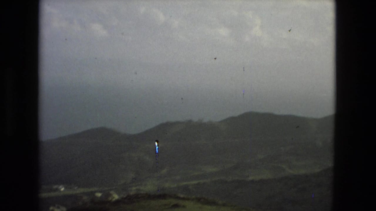 Distant hills under cloudy sky seen through dark 8mm frame edges.