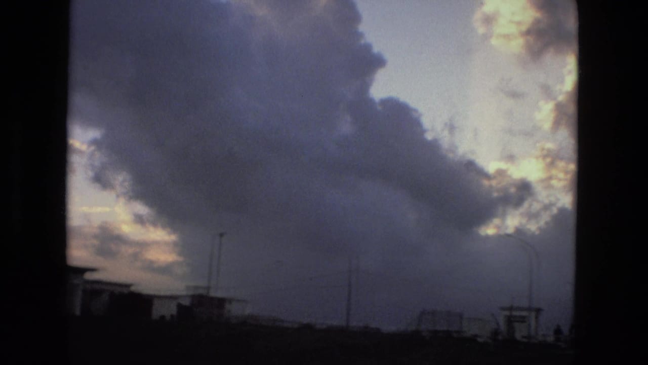 Dark clouds and bright sky above low street silhouettes.