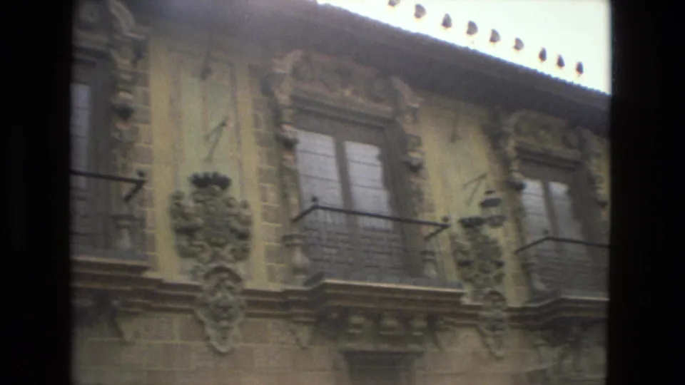 The camera pans across the Córdoba building facade, showing paired windows, balconies, carved trim, and a hanging exterior lamp.