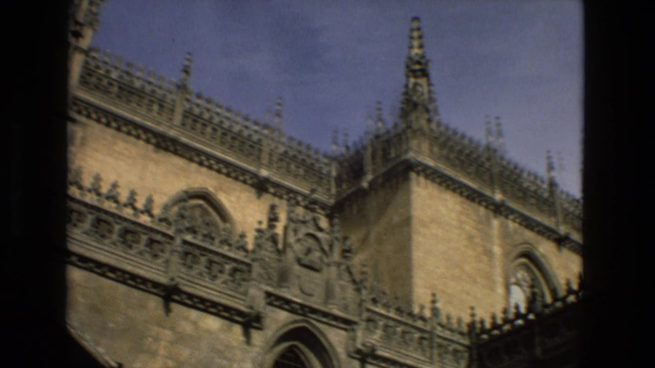 Gothic church exterior with ornate roofline, spires, arched window, and blue sky.