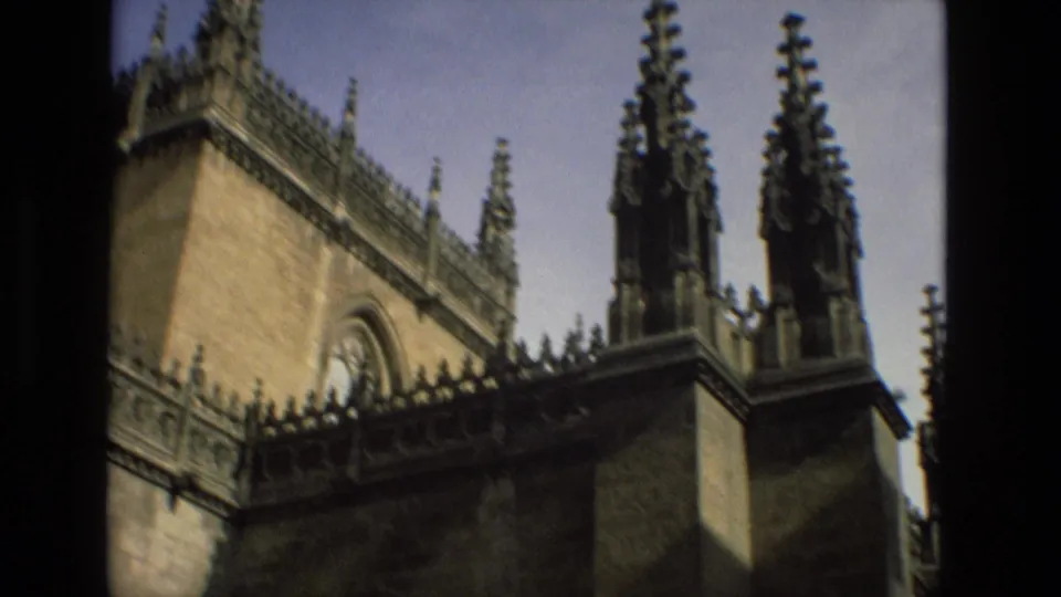 1978 Cordoba frame of a historic church exterior, showing warm stone walls, pointed spires, roofline ornament, and a clear sky.