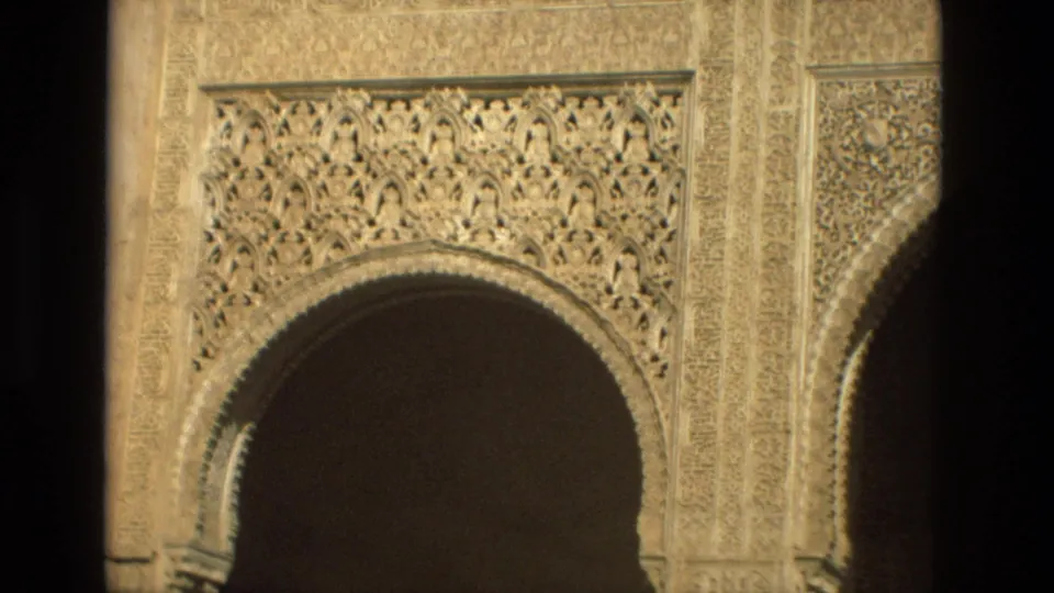1978 Córdoba frame of an ornate carved horseshoe arch with dense geometric and arabesque stone decoration around a dark opening.