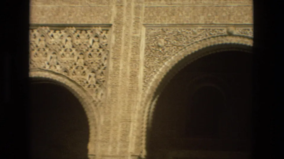 1978 Córdoba home-movie view of carved stone panels and a horseshoe arch, partly blocked by dark foreground framing.