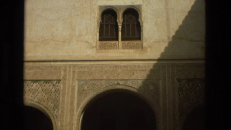 1978 8mm Córdoba frame with twin arched windows, ornamental wall bands, and strong sunlight casting a large diagonal shadow.