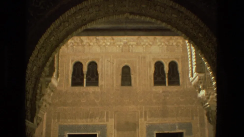 The 8mm frame looks through a shaded arch toward an ornate Córdoba courtyard facade with small windows and tile panels.