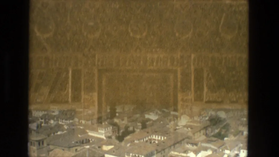 Spain travel footage frame combining decorative architectural surface with a distant hillside city view below.