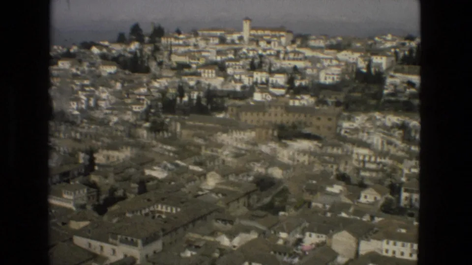 1978 8mm frame showing an elevated view over a dense Spanish cityscape with white buildings and tiled roofs.