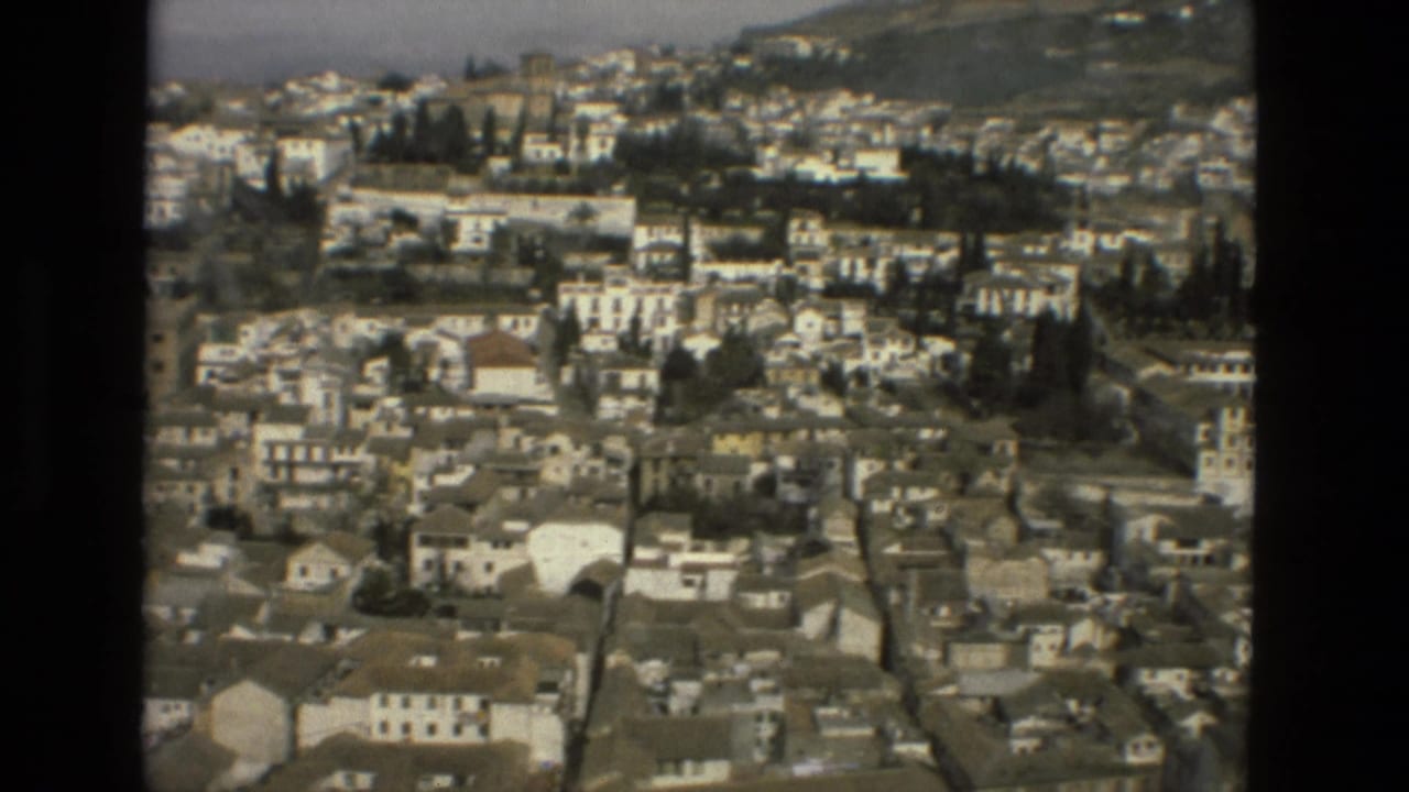 Elevated view over whitewashed buildings and rooftops below a hillside.