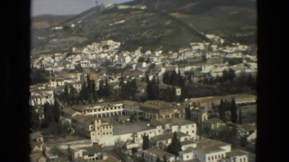 1978 Córdoba hillside view showing clustered white homes, cypress-like trees, low-rise buildings, rooftops, and sloping green terrain.