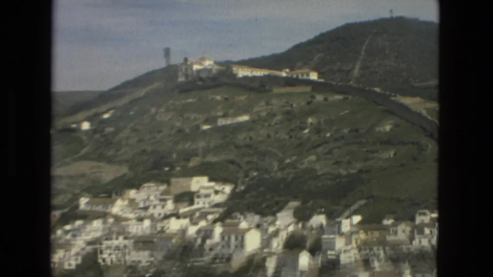 1978 Córdoba view toward a green hill with a prominent structure near the ridge and white buildings gathered along the lower slope.