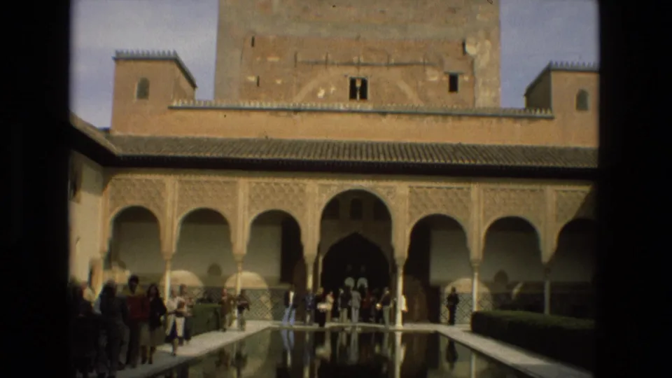 Tourists stand near the Alcázar of Córdoba reflecting pool beneath ornate arches in 1978 home-movie footage.