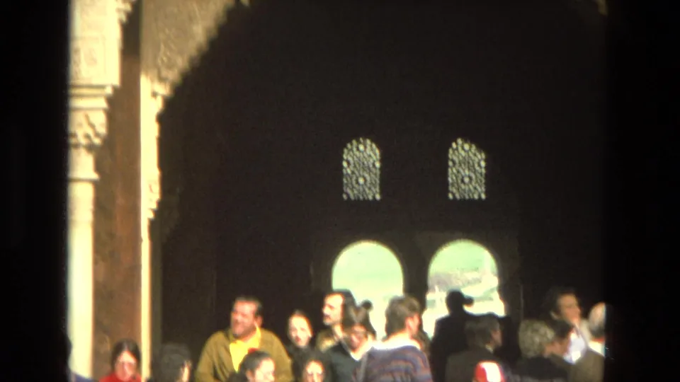 Tourists in 1978 Cordoba stand beneath arched openings and carved architecture in a historic site.