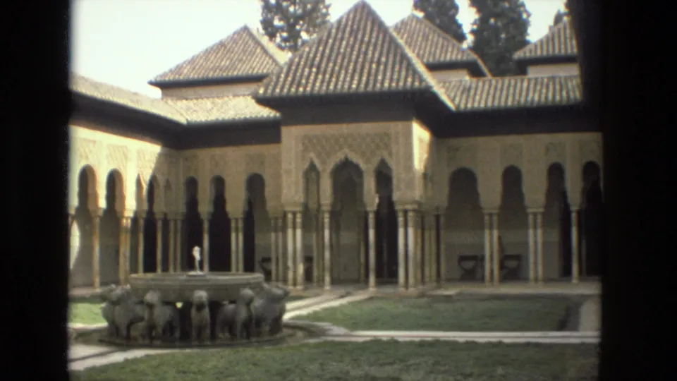 Cordoba courtyard in 1978 with tiled roofs, arched colonnade, lawn and a stone lion fountain.