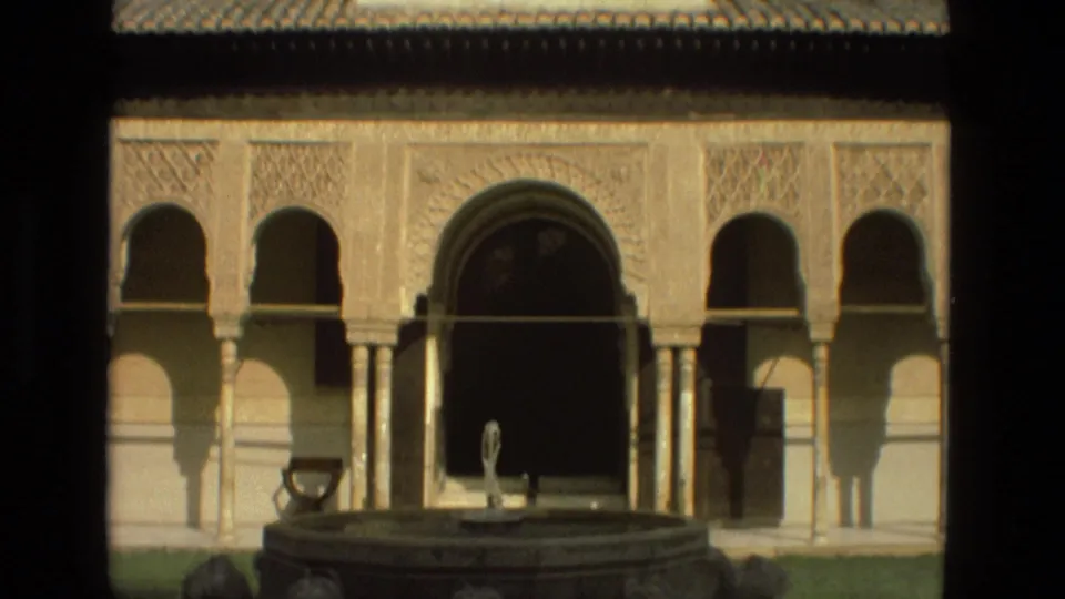 Sunlit 1978 Córdoba courtyard view with arched colonnade, carved facade detail, and a central fountain basin in the foreground.