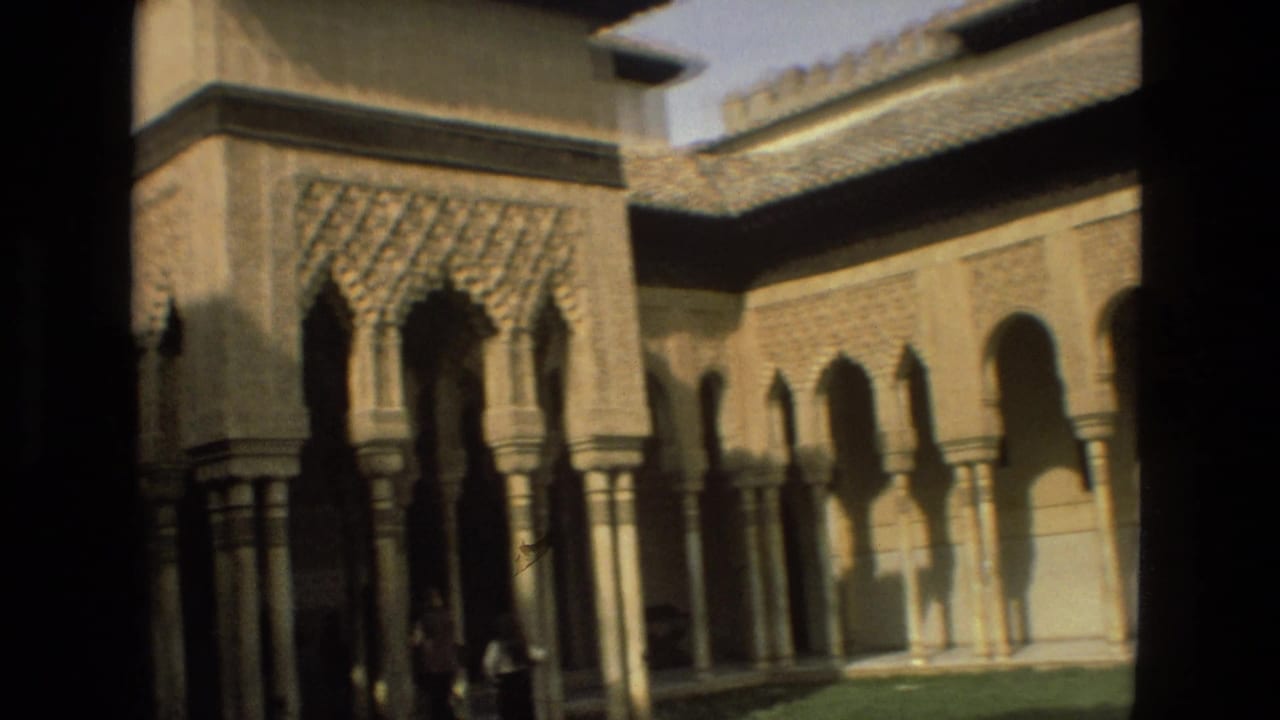 1978 8mm view in Córdoba showing Moorish-style arches, stone columns, tiled roofs, and a shadowed courtyard edge.