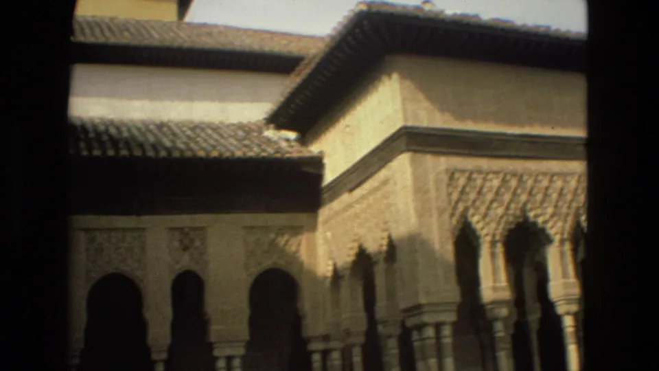 Córdoba landmark courtyard in 1978, with arched openings, carved stone panels, tiled rooflines, and heavy shadow from the walkway.