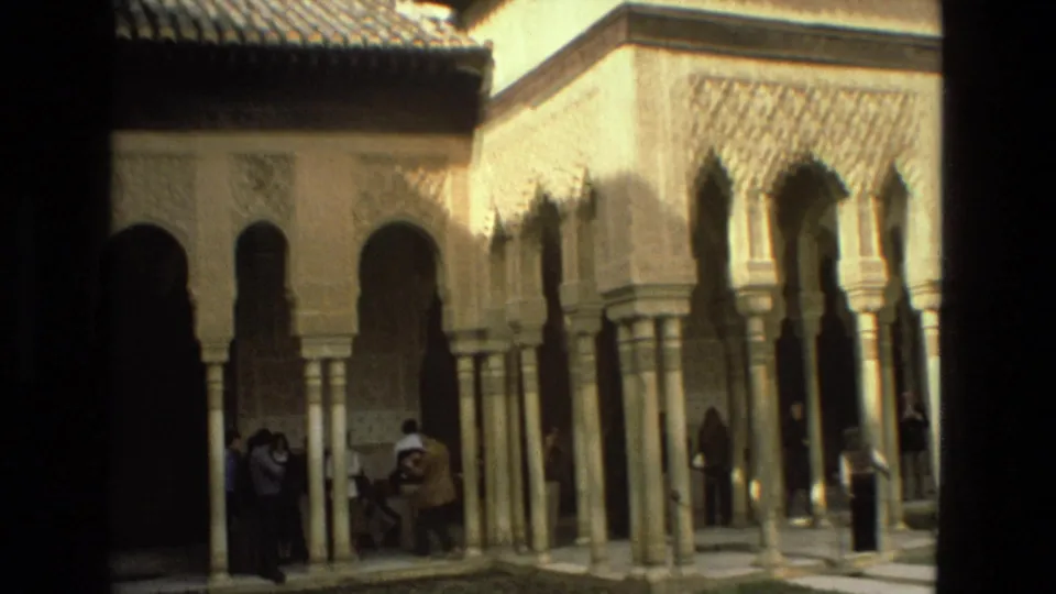 1978 Córdoba courtyard scene with visitors near slender columns, horseshoe arches, carved walls, and tiled rooflines.
