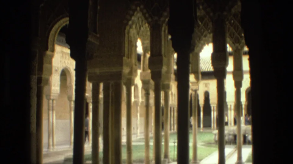1978 8mm view in Cordoba through shadowed columns toward Moorish-style arches and a bright courtyard garden.