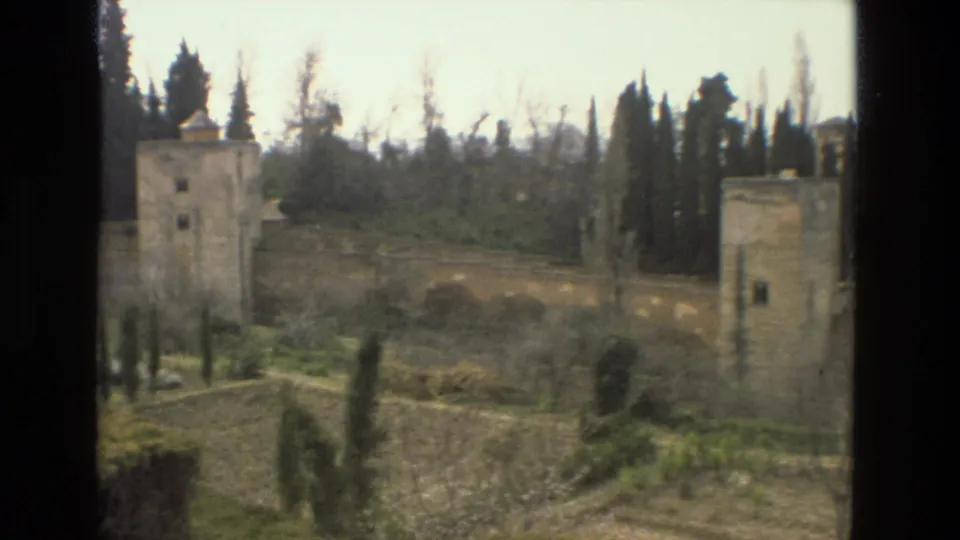 1978 8mm footage of the Alcazar gardens in Cordoba showing stone towers, walls, cypress trees, and planted garden sections.