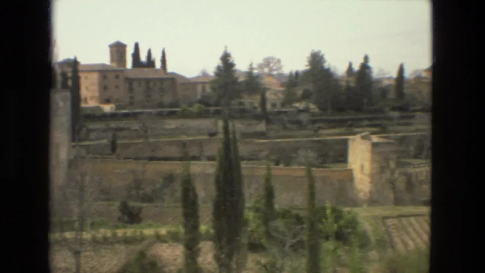 1978 8mm view over Córdoba with stone fortifications, cypress trees, terraced gardens, and historic buildings beyond.