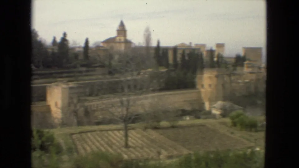 Córdoba panorama showing fortified walls, garden terraces, cypress trees, and distant historic architecture on 8mm film.