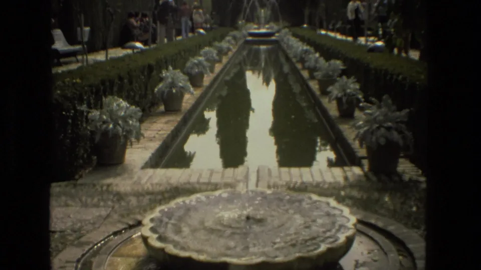 A formal Cordoba garden scene shows a long reflecting pool, potted plants, clipped hedges, trees, and visitors gathered along the sides.