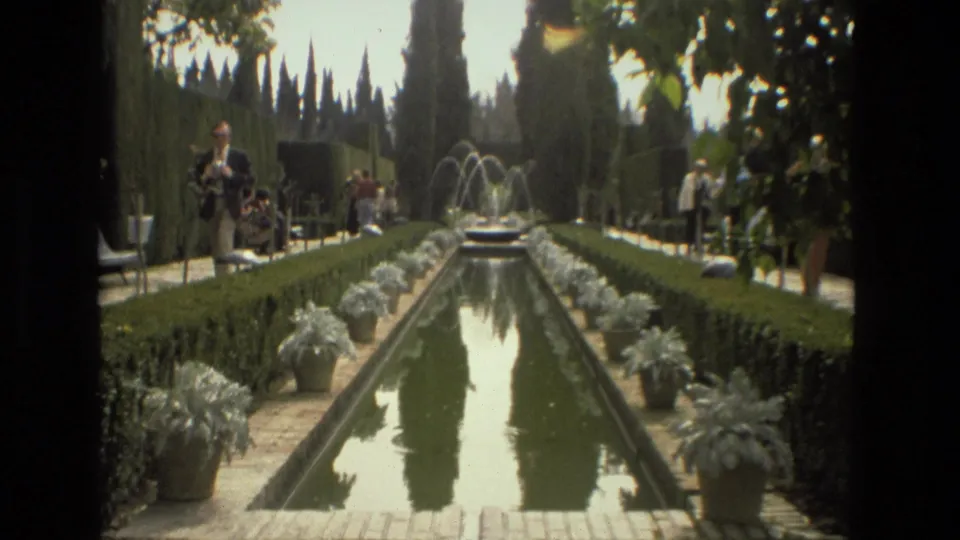 The 1978 Cordoba garden footage shows a reflecting pool with small fountains, cypress trees, potted plants, clipped hedges, and visitors in the background.