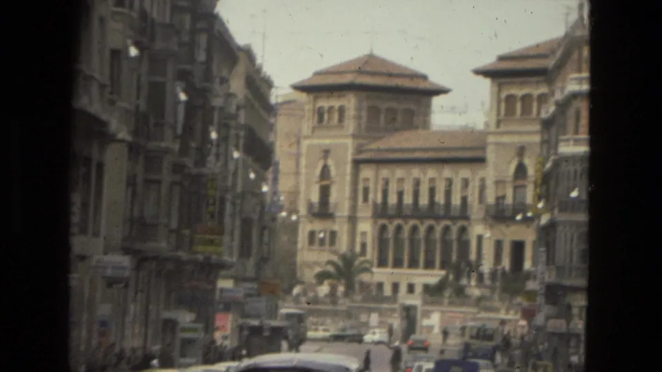 Córdoba street scene with moving and parked cars, pedestrians, and a historic-looking arched building visible ahead.