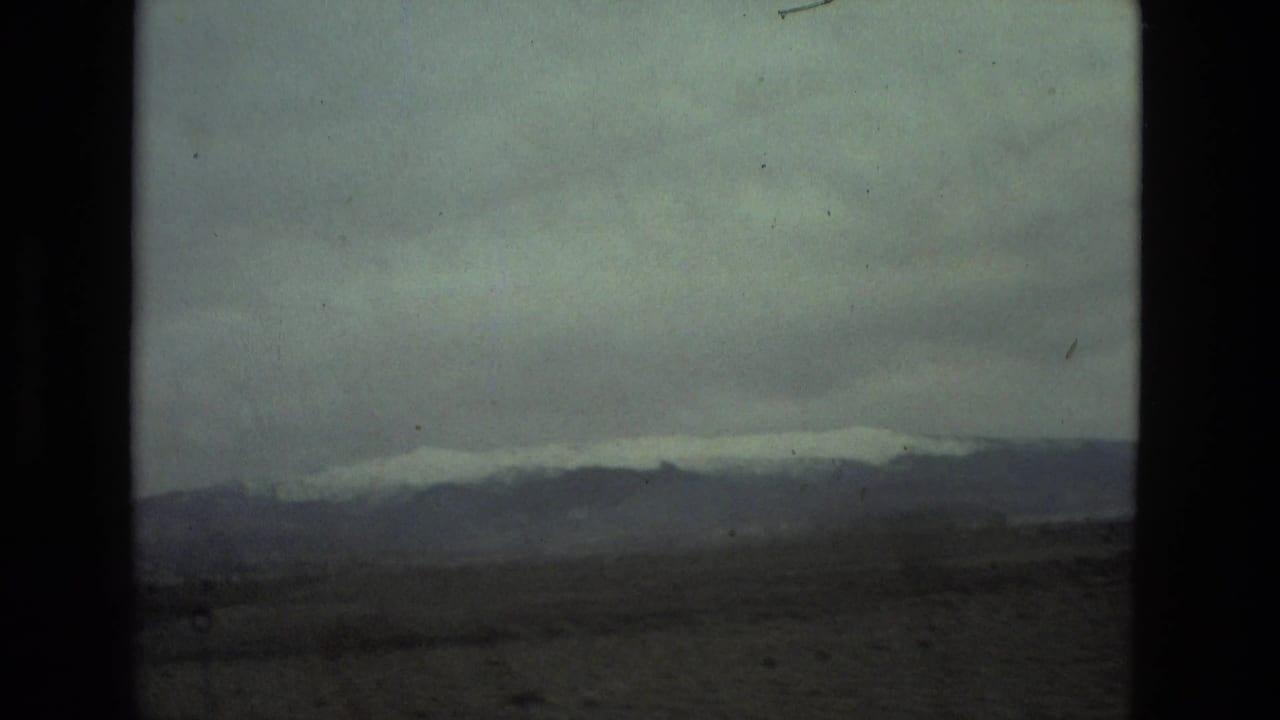 1978 8mm view of a distant mountainous landscape near Seville, Spain, with haze, muted exposure, and dark frame edges.