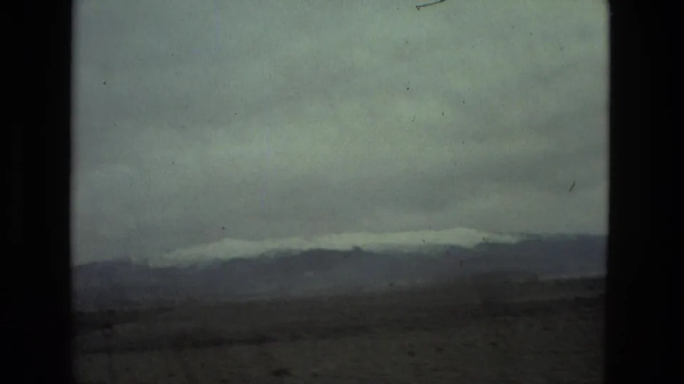 1978 8mm view of a distant mountainous landscape near Seville, Spain, with haze, muted exposure, and dark frame edges.
