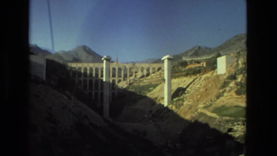 Handheld 1978 8mm view of the arched structure, white supports, and rugged terrain in the Seville, Spain metadata location.