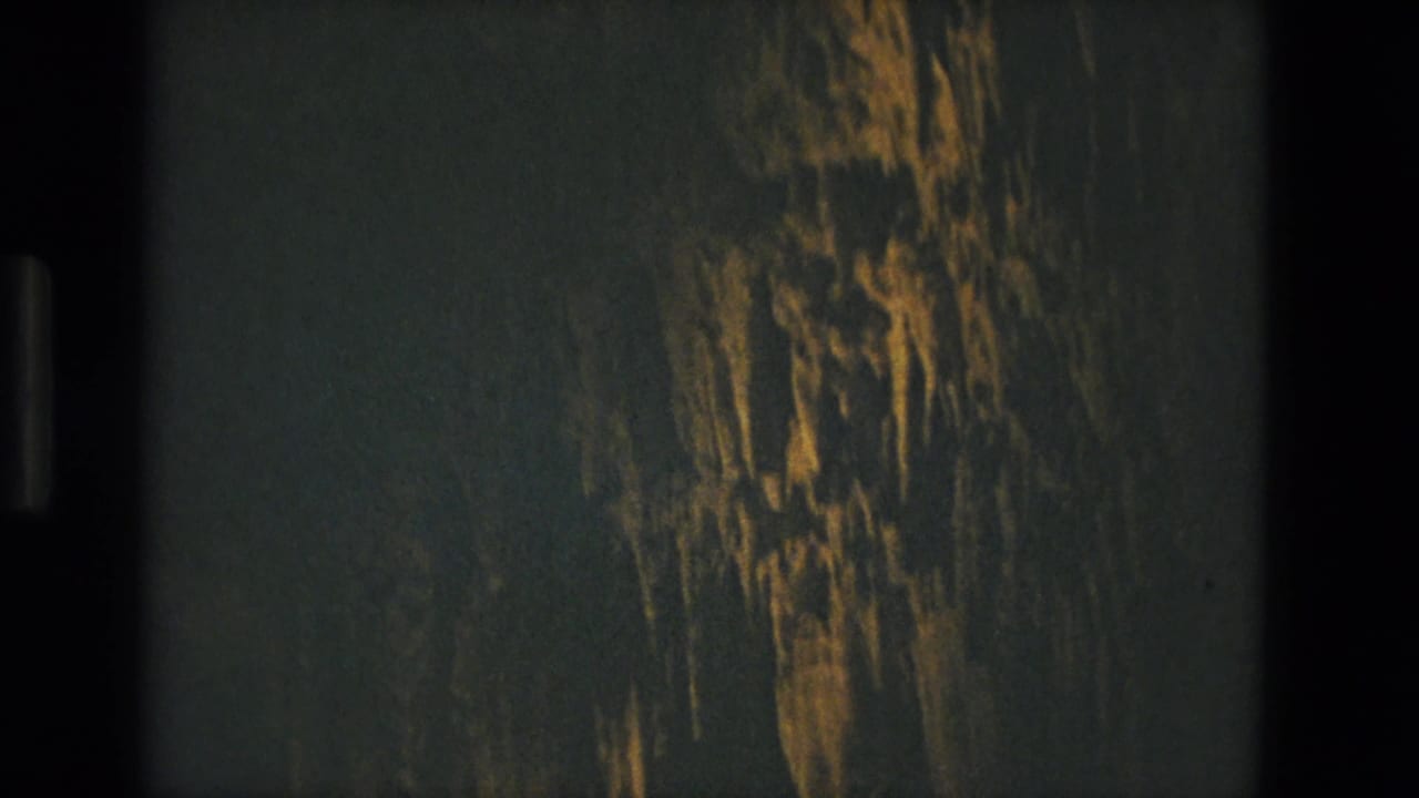 Dark grainy tunnel surface with warm vertical light streaks and film border visible.