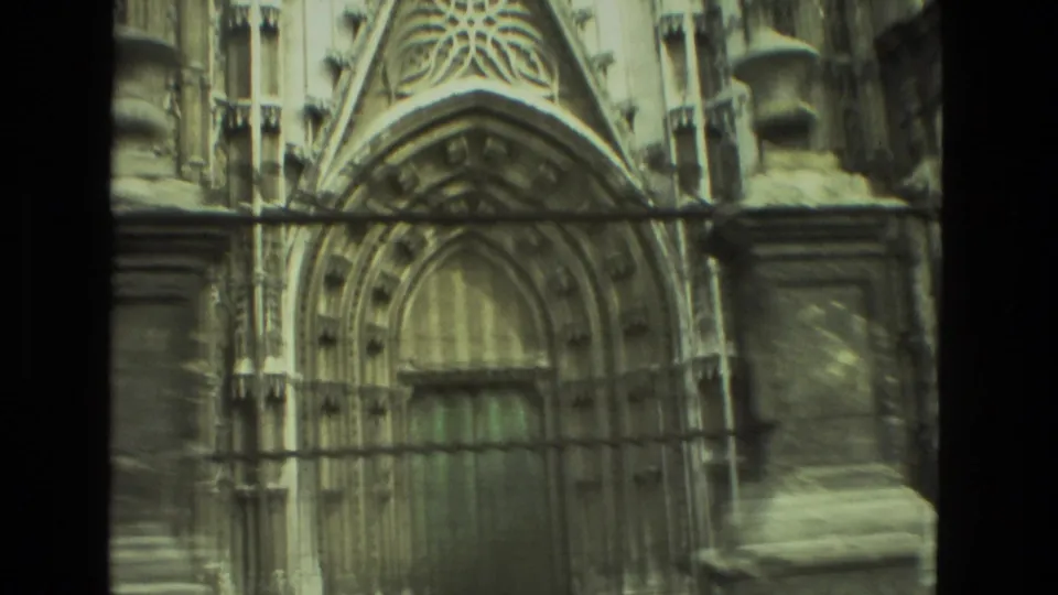 Seville 1978 home-movie frame showing an ornate arched doorway and weathered stone facade in muted 8mm color.