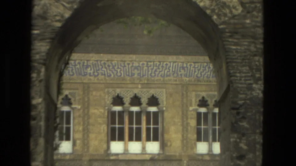 Seville 1978 frame showing a closer view through a weathered arch toward ornate windows and patterned architectural decoration.