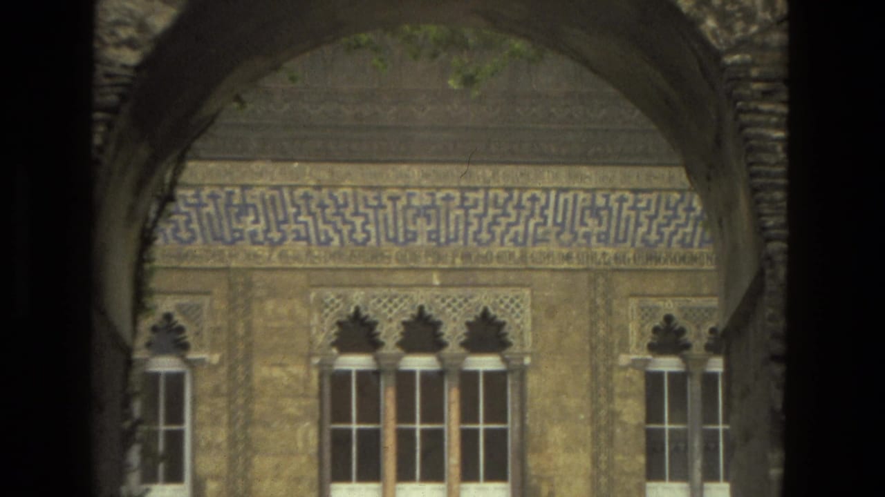 Ornate arched windows and blue tile inscription seen through a dark archway.