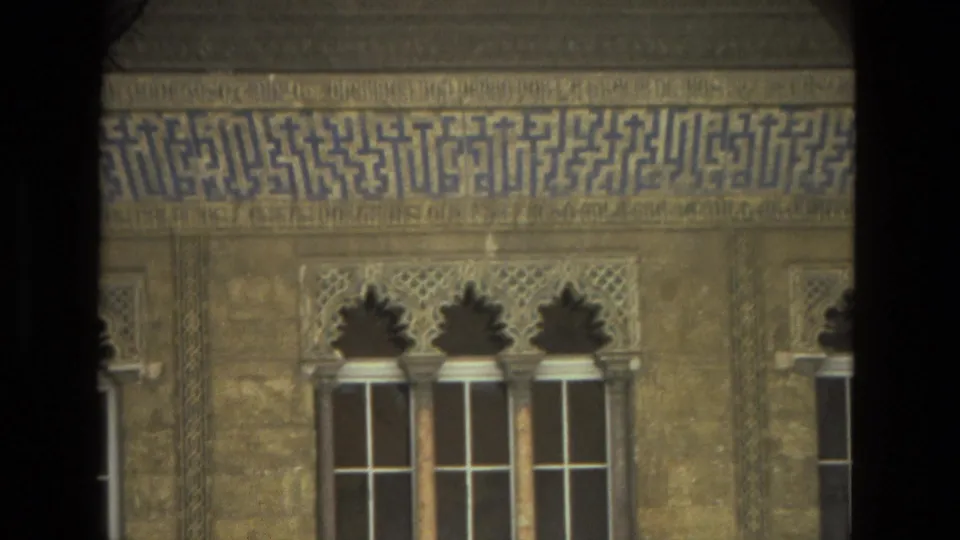 1978 Seville architectural detail showing a row of arched windows, blue tile lettering, and carved exterior ornament behind a dark foreground column.