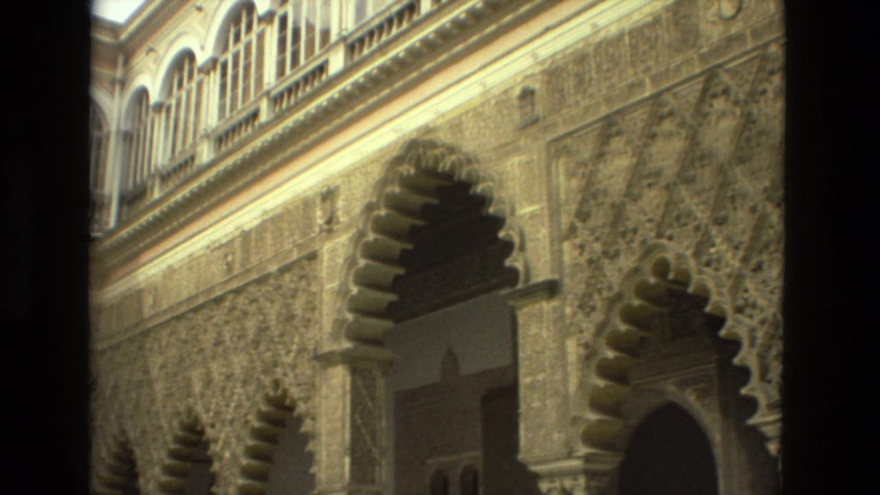 Ornate courtyard wall with scalloped arches and upper arched windows.
