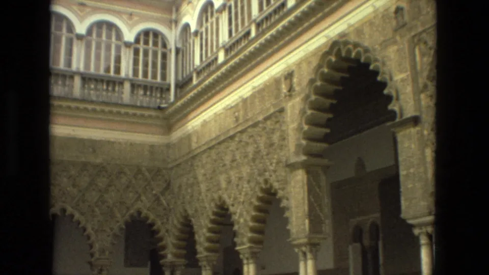 The Seville courtyard appears from a slightly rotated angle, showing upper arched windows, decorative stonework, and deep scalloped arch openings.