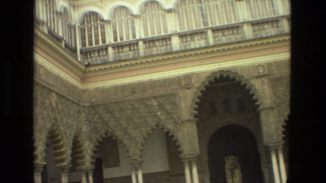 Ornate courtyard wall with scalloped arches and an upper gallery.