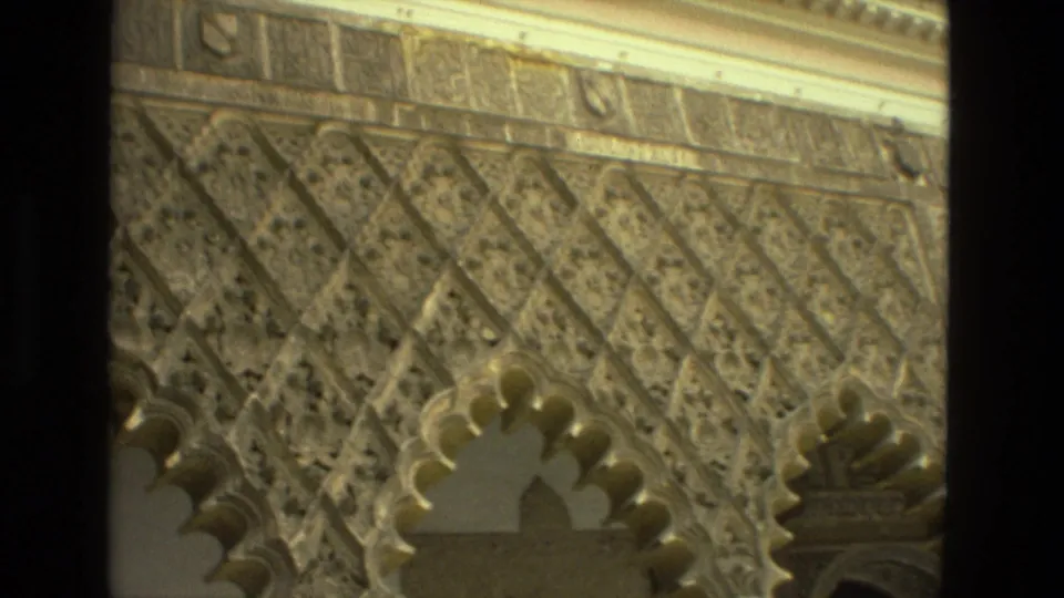 1978 Seville frame showing patterned courtyard wall decoration, paired scalloped arches, and layered stone or plaster ornament.