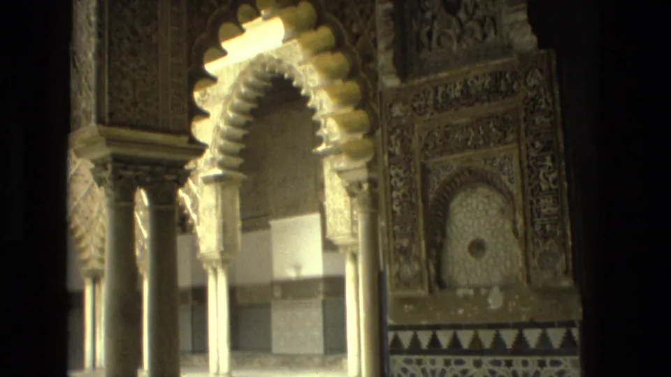 1978 8mm frame from Seville with a close visitor angle on an ornate horseshoe arch, columns, carved wall detail, and patterned tilework.