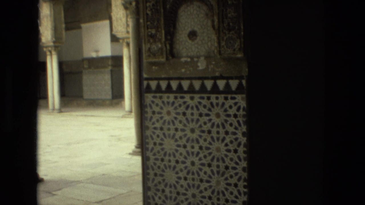 Tiled wall and columns seen through a dark doorway.